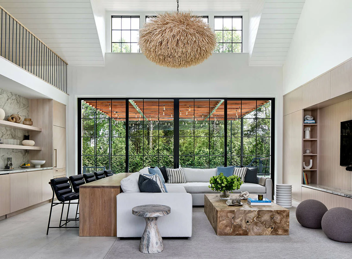 The light-filled pool house interiors feature large glass siding doors and neutral furnishings for a comfortable, airy feel. 