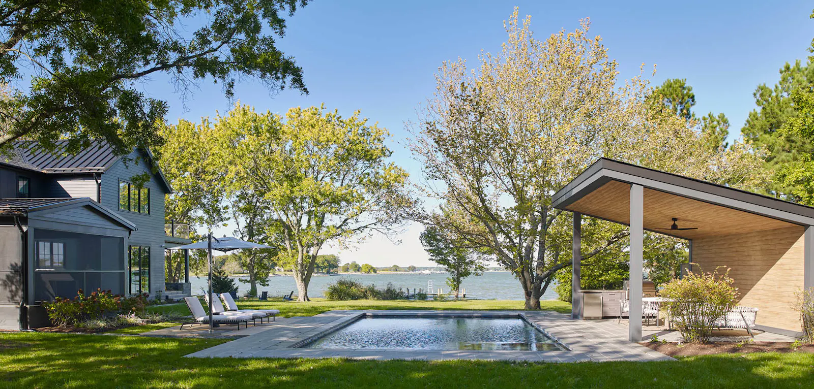 A view of the landscaped exterior, featuring a pool and a pool pavilion