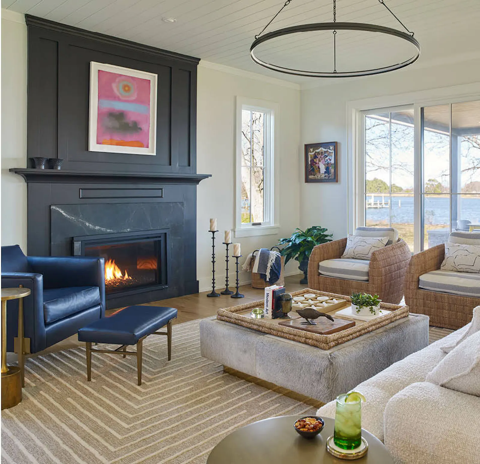 Living spaces inside the waterfront farmhouse, including a comfortable living room with a black statement fireplace and a welcoming foyer with updated stairwell