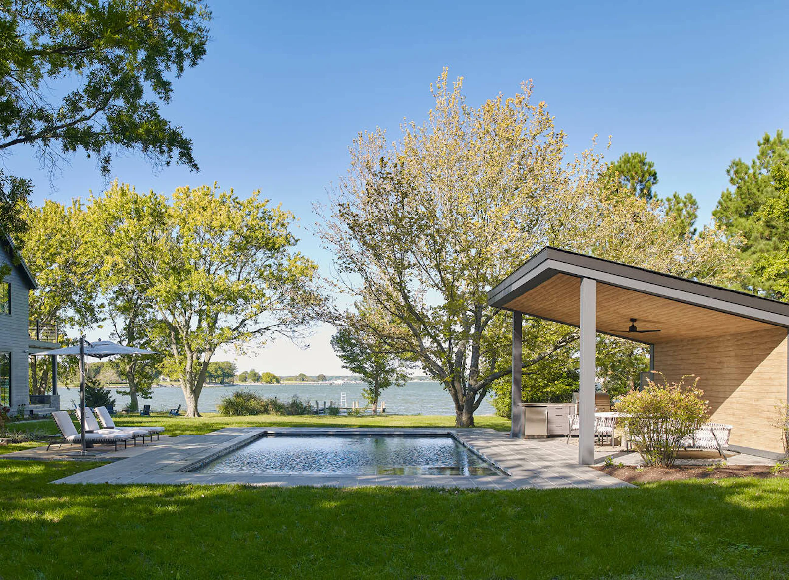A view of the landscaped exterior, featuring a pool and a pool pavilion