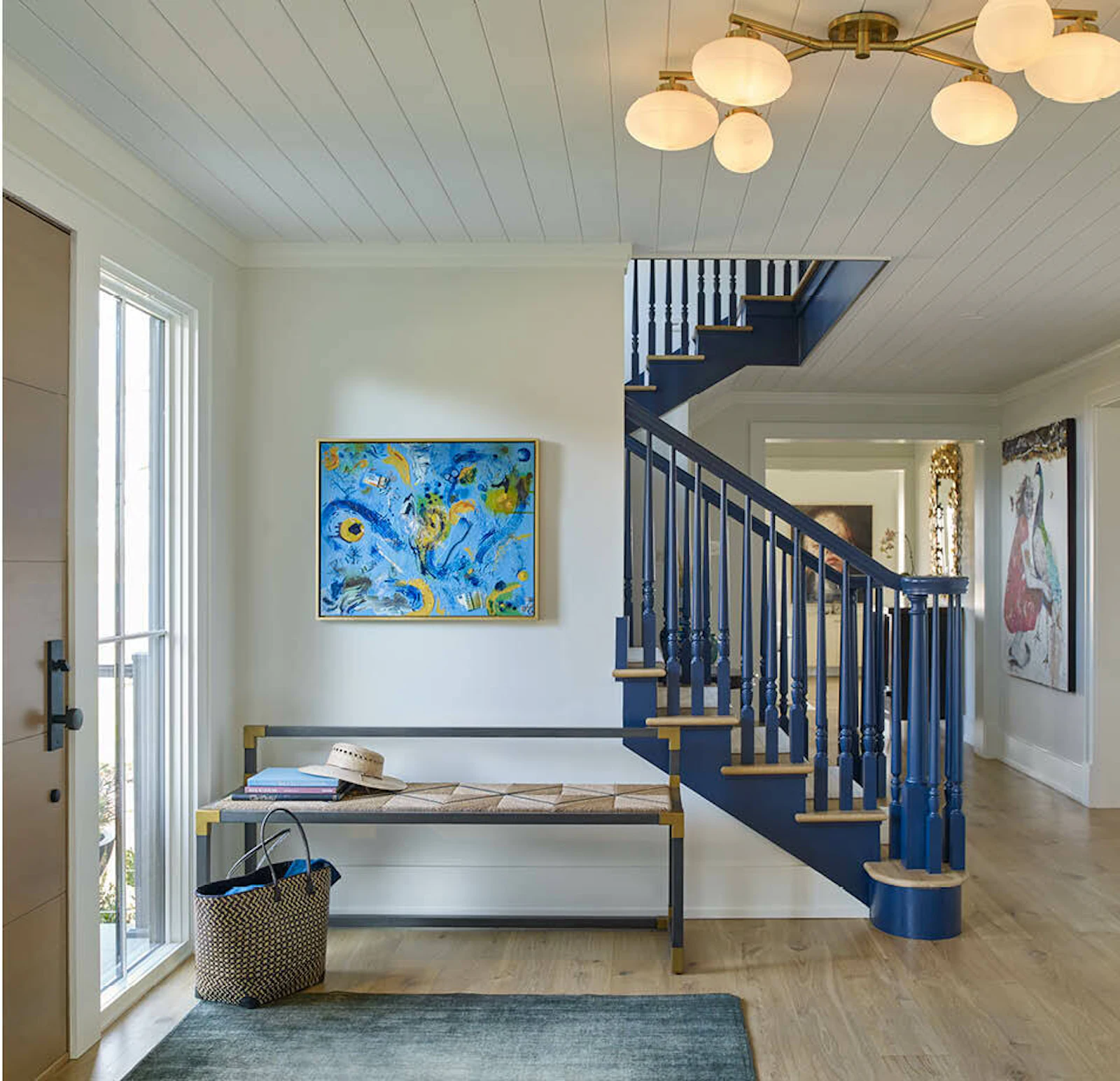 Living spaces inside the waterfront farmhouse, including a comfortable living room with a black statement fireplace and a welcoming foyer with updated stairwell
