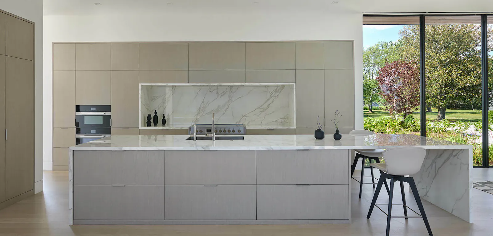 A minimalist white kitchen offers built-in fixtures and hidden appliances. 