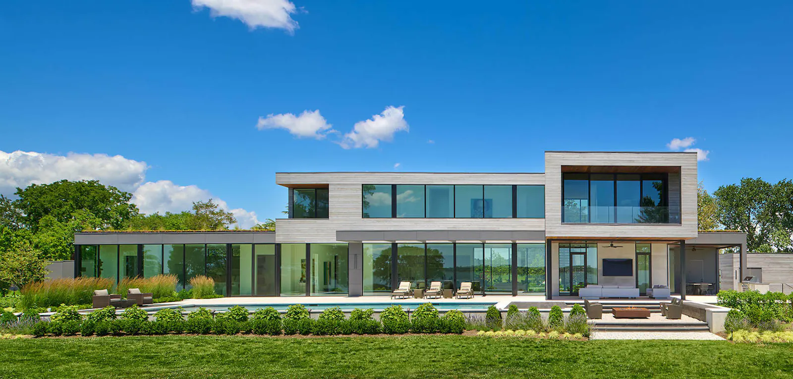 The home's exterior facade shows almost entire walls of windows. 
