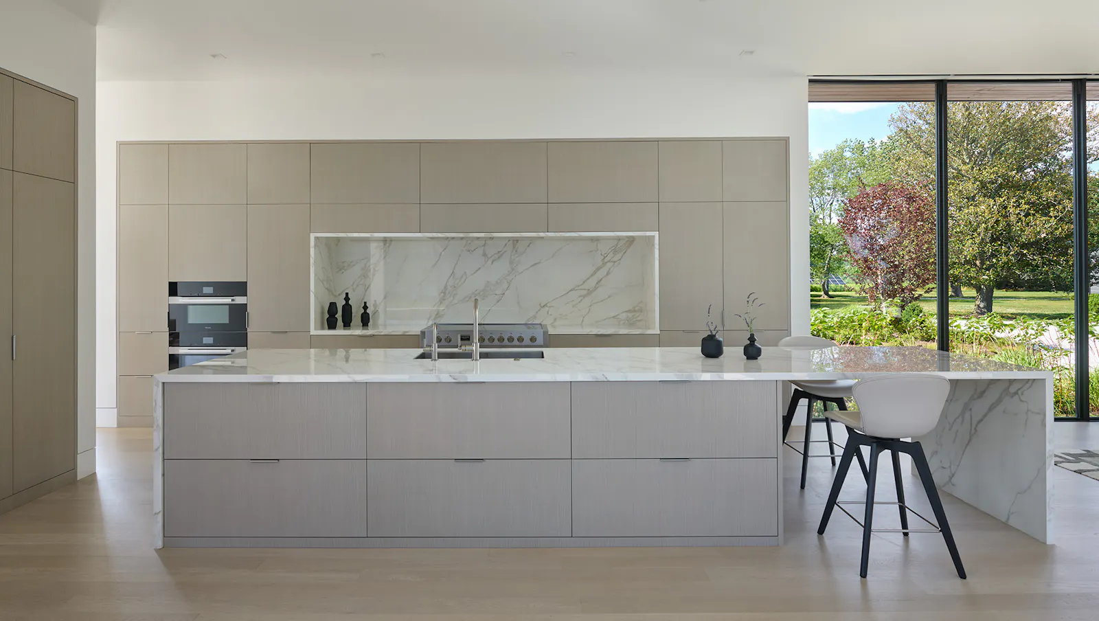 A minimalist kitchen features calacatta neolitch kitchen counters that emulate marble and neutral cabinetry. 
