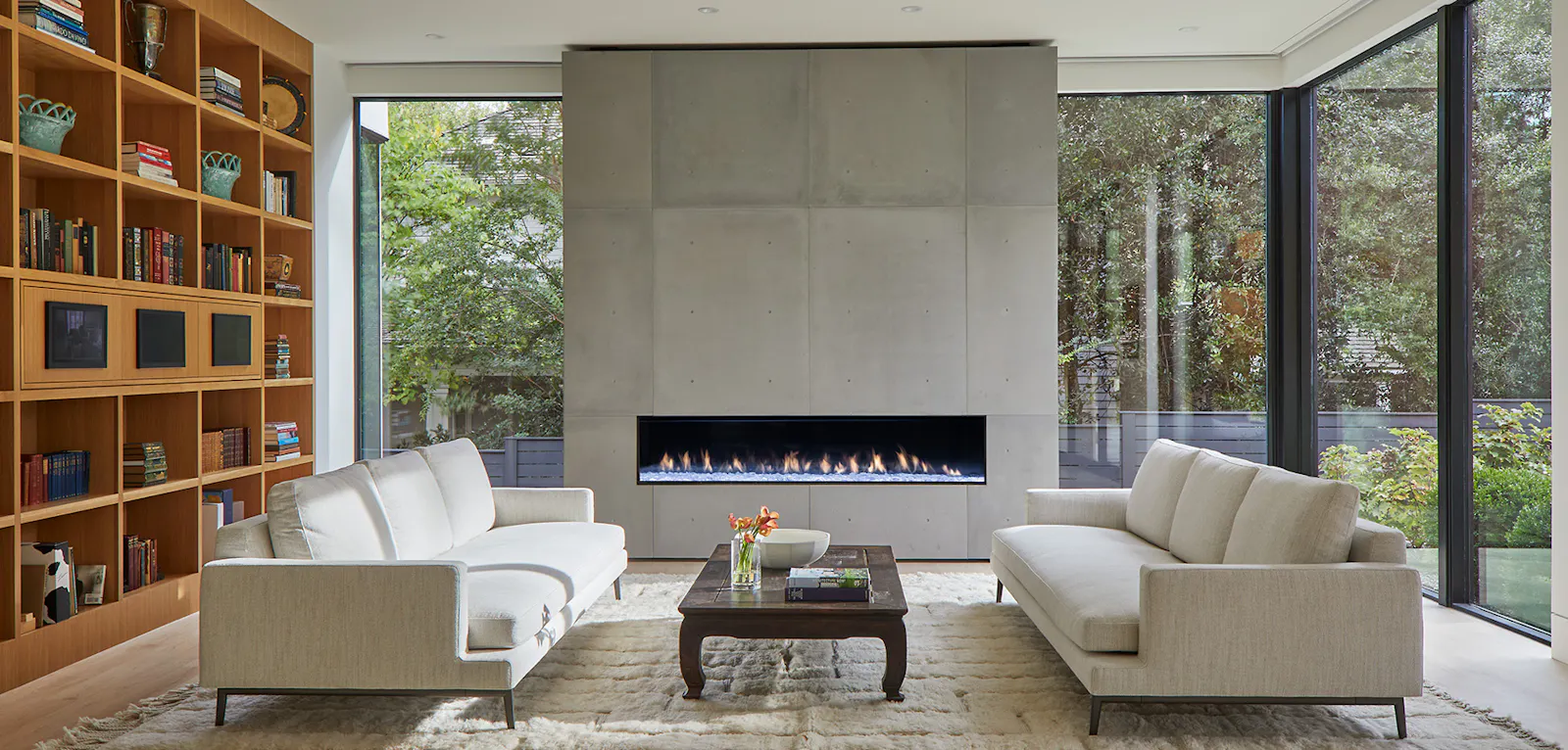 A statement concrete fireplace is surrounded by glazing. 