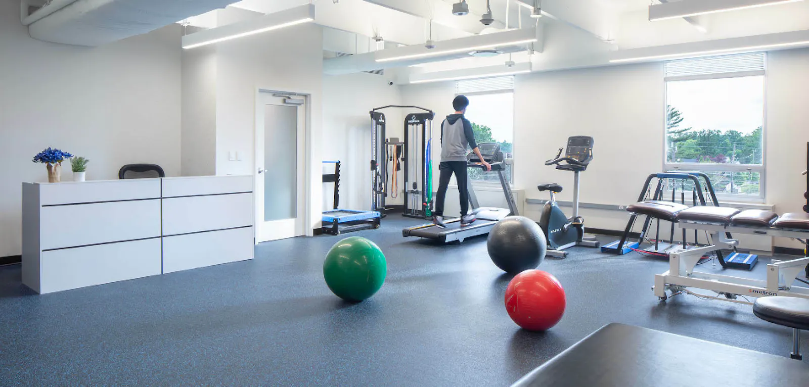 A person walks on a treadmill in an exercise and physical therapy room at the Neurology, Headache & Pain Institute. 