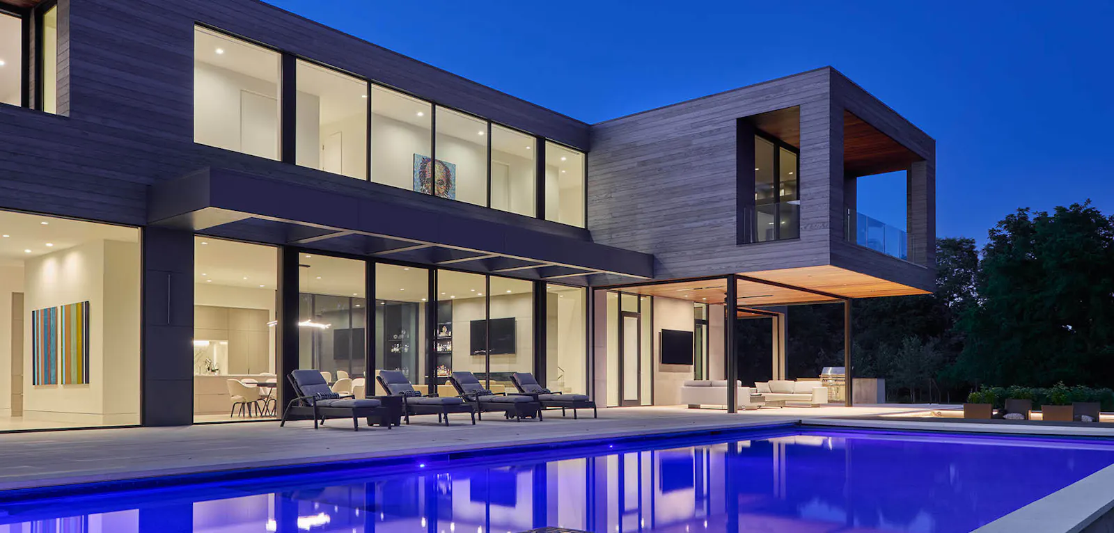The dusk view of the contemporary home with a pool 