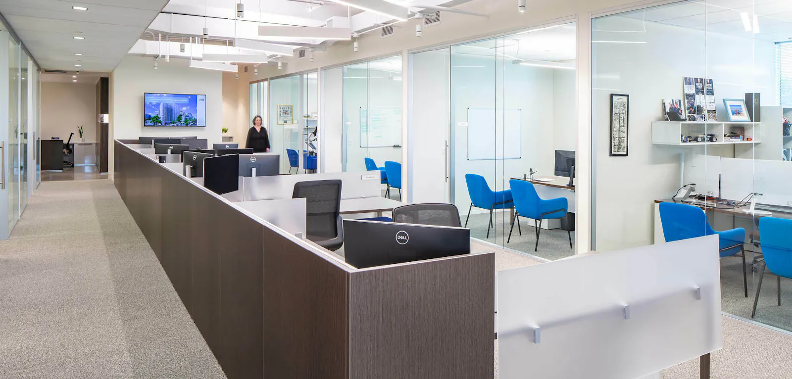 KLNB's renovated office at Park Potomac, featuring wood-front workstations, glass-front offices, and blue chairs
